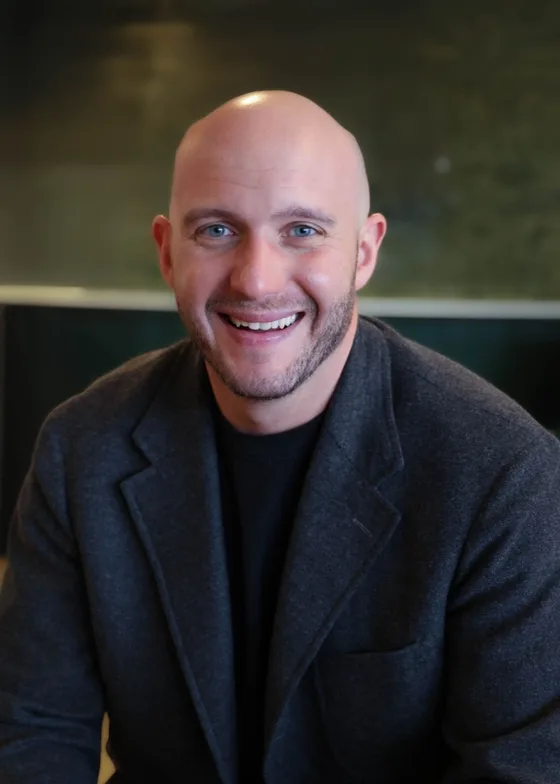 Paul Albarrán, smiling, in a charcoal blazer over a black shirt.